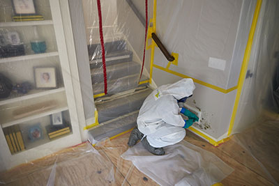 Mold technician treating mold on a wall with ventilation place